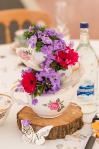 Red and purple flowers in vases at vintage wedding in Warwickshire