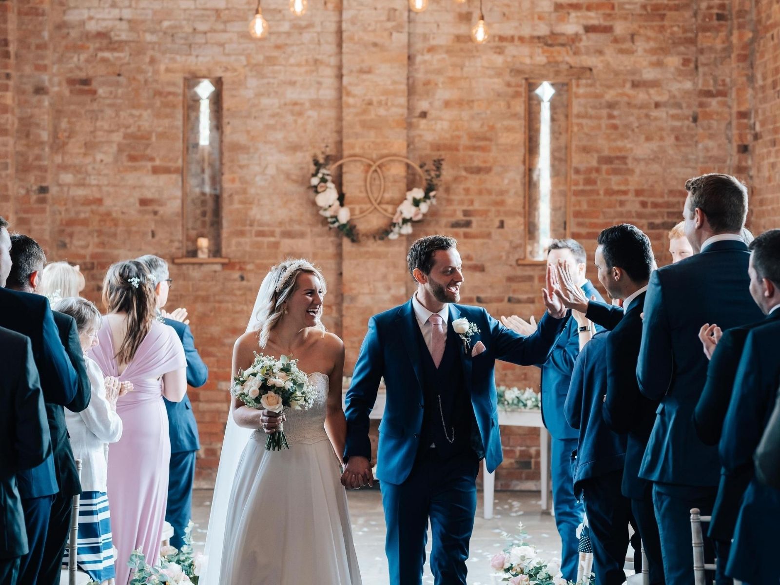 Bride holding wedding flowers leaving barn wedding ceremony