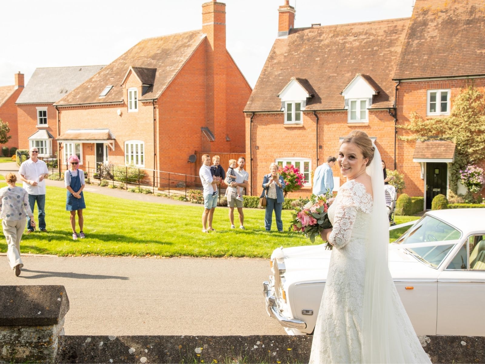 Boho Bride Rachel outside her church, socially distancing from guests on the green opposite